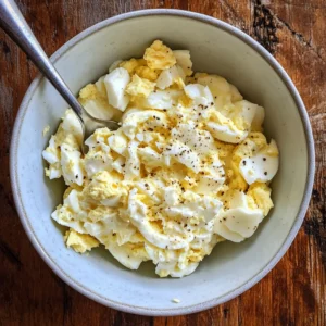Mixing chopped eggs with Greek yogurt dressing for high protein healthy egg salad