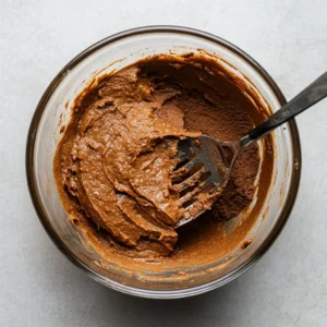 Adding cocoa powder, protein powder, and salt to brownie mixture